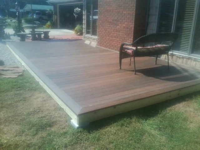 New wood deck and wicker chair beside a brick house in Liberty Center