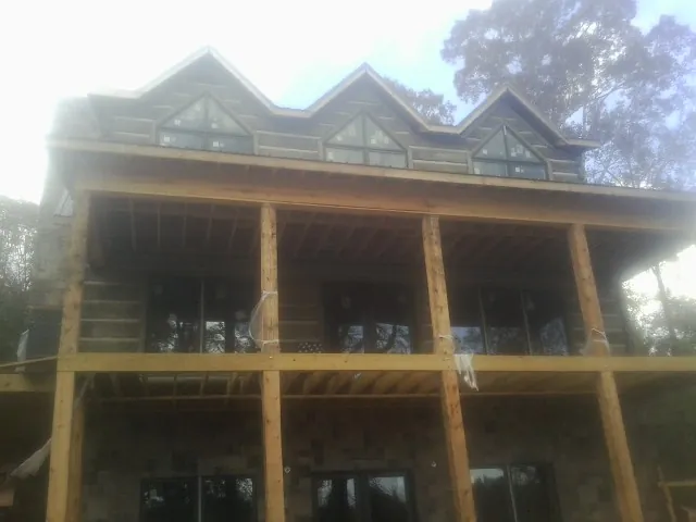 Dormers and porch framing on a large log home under construction — Roof Coating work by our crew in Liberty Center