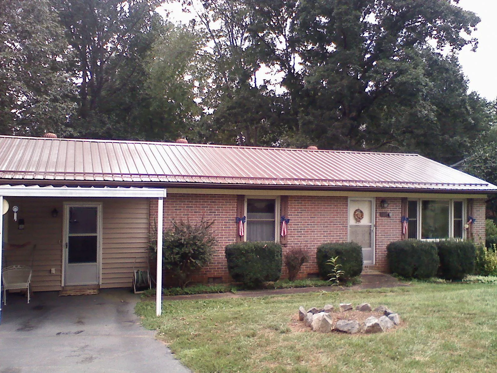 Bronze metal roof and carport on a brick ranch home — Roof Repair work by our crew in Liberty Center